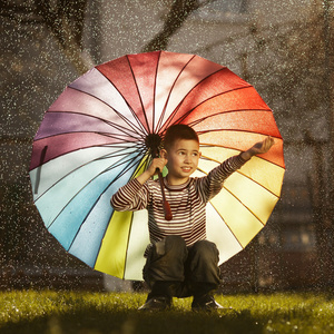 快乐的男孩，在公园里的彩虹伞