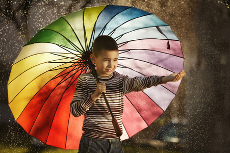 快乐的男孩，在公园里的彩虹伞