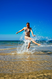 飞溅。水在海滩上享受的年轻女人。夏季