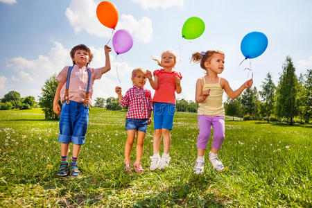 带着四个气球的小孩子在绿草地上