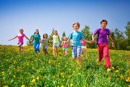 绿色草地上牵着手奔跑的孩子们