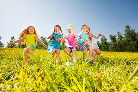 快乐的孩子们在黄色的草地上踢足球