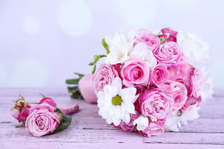 美丽的婚礼花束和明亮的背景上表格的胸花