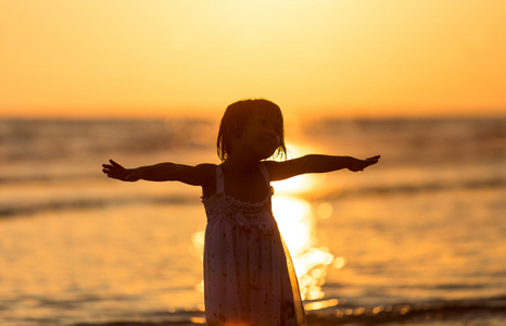 快乐的女孩，站在海滩上的黎明时期