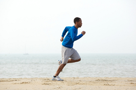 年轻男性慢跑锻炼在沙滩上