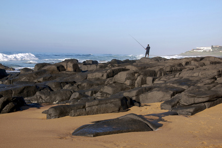 在 ballito 海滩岩石上垂钓孤翁