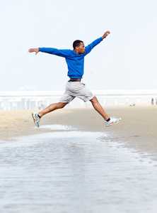 健壮的男人，跑步和跳跃在海滩