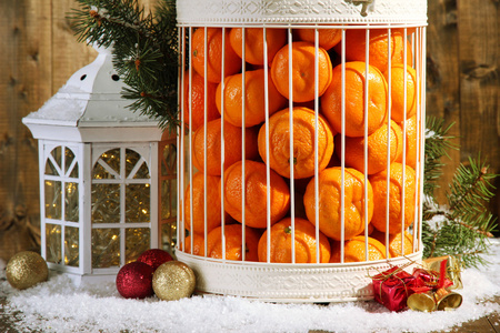 橘子装饰圣诞装饰，木制的背景上的笼子里