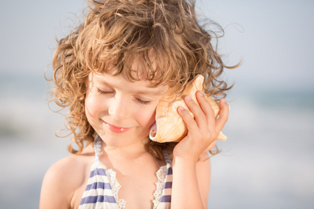 快乐的孩子听在海边的贝壳