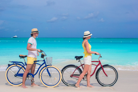 年轻幸福的夫妇，在白色的沙滩上骑自行车