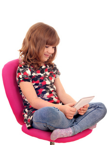 快乐的小女孩坐在椅子和 tablet pc 一起玩