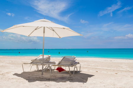 白色的伞和在地处热带的海滩日光浴浴床
