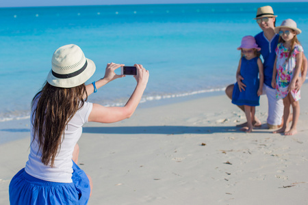年轻的母亲照片制作电话她家人在海滩上