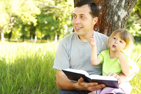 年轻的父亲带着女儿读圣经 