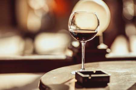 红葡萄酒杯，在一家咖啡馆的桌子上的烟灰缸