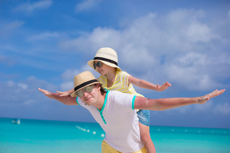 快乐的父亲和他可爱的小女儿在地处热带的海滩玩得开心