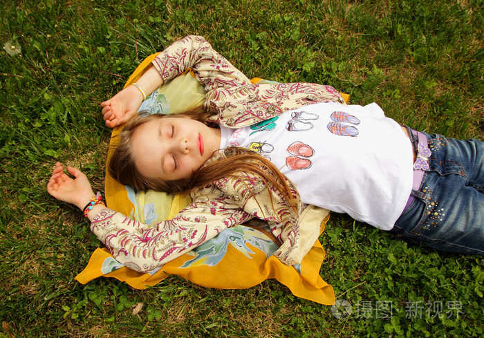 漂亮的小女孩躺在草地上,闭着眼睛