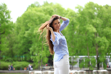 幸福的年轻女人，在白色的裤子和蓝色的衬衫