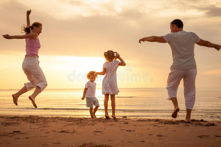 快乐的家庭在海滩上跳跃