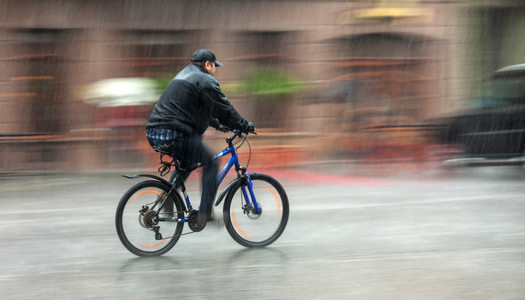 cyklist Rider genom gatorna p en regnig dag