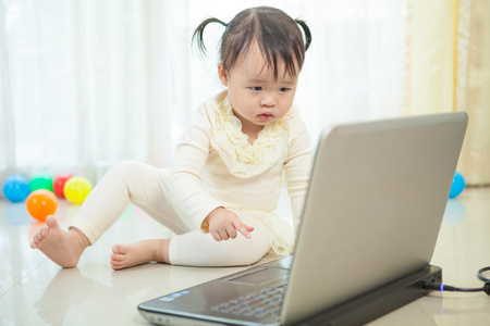 小亚洲女孩玩手提电脑在家里
