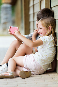 快乐年轻的兄弟与她的智能手机拍照以 p