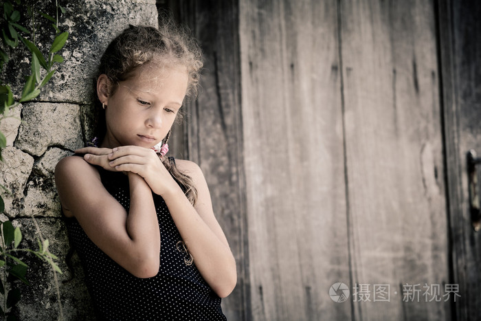 悲伤的小女孩,在这一天站在石头墙附近的肖像