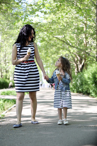 快乐妈妈和女儿。在绿色的公园散步