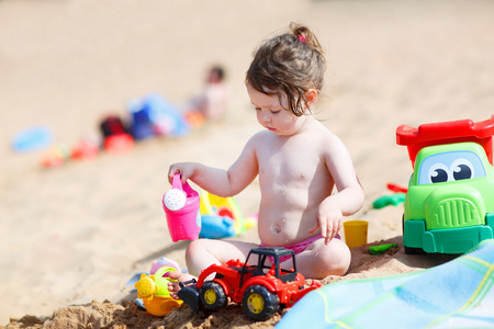 蹒跚学步的小姑娘在沙滩上玩沙玩具