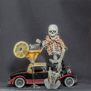 坐在经典的汽车持有汽车钥匙和酒精饮料的骨架
