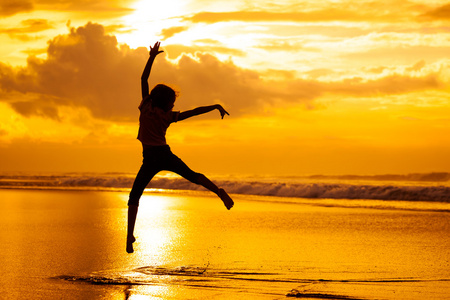 上的黎明时间在海滩上跳跃的快乐女孩