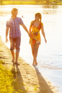 幸福的夫妇在海滩上散步的爱。夏季假期浓