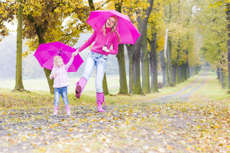 母亲和她的女儿在秋季小巷遮阳伞