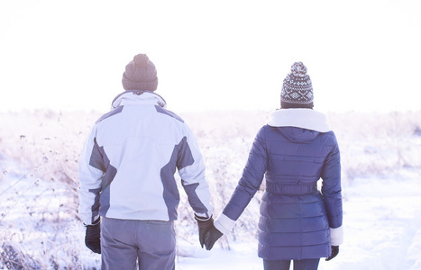 对年轻的夫妇手牵手在冬天的旷野上