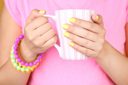 时尚多彩的指甲，拿着杯子，特写，在彩色背景上的女人