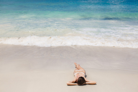 年轻女子躺在地处热带的海滩上