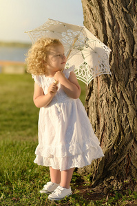 年轻漂亮的女孩穿白色连衣裙的相机摆姿势
