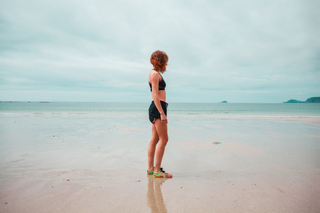 站在海滩上的健身服的年轻女子
