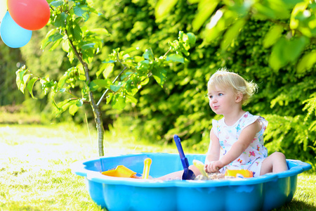 快乐的小女孩，在一个阳光明媚的夏日户外玩沙盒