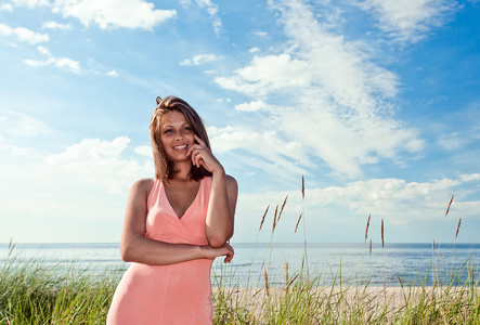 美丽的女孩在海滩上的粉红色的连衣裙