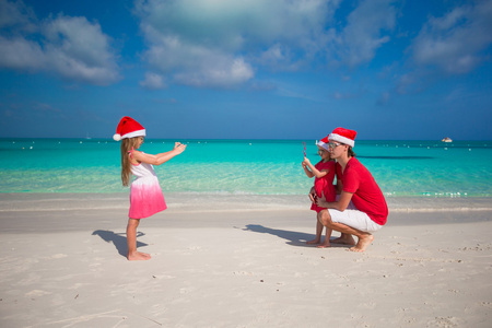 在电话的父亲和姐姐在海滩上的照片制作的可爱的小女孩