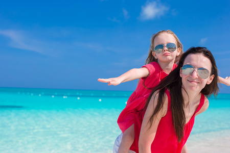 年轻的妈妈和小女孩在地处热带的海滩玩得开心