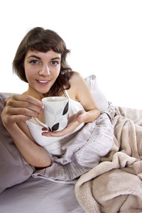 在早晨喝咖啡在床上的女人