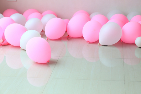 背景白色墙上与地上的粉红色和白色气球