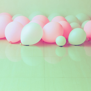 背景白色墙上与地上的粉红色和白色气球