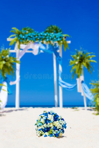 热带沙滩上用鲜花装饰的结婚拱门，户外海滩婚礼设置
