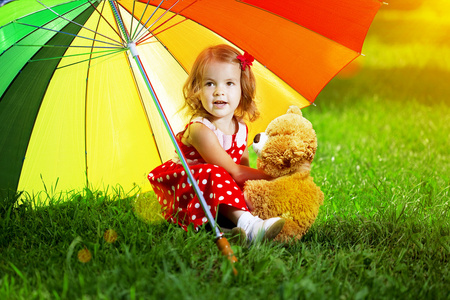 快乐的小女孩在公园里的彩虹伞。孩子在玩