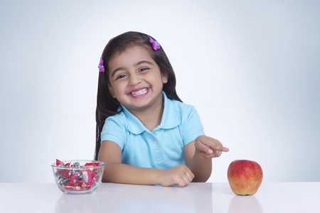苹果和甜的食物之间进行选择的女孩
