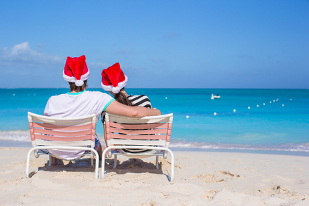 年轻的夫妇，在圣诞老人的帽子后面观享受海滩度假