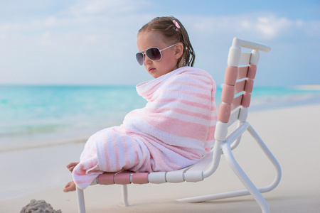可爱的小女孩在太阳镜满在地处热带的海滩毛巾